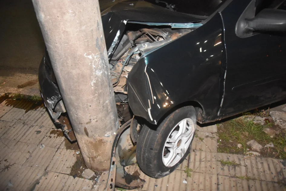 Automóvil negro con severos daños frontales tras chocar contra una columna de hormigón.